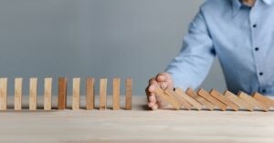 Businessman hand stopping the domino wooden effect concept for Planning,risk and strategy in business.